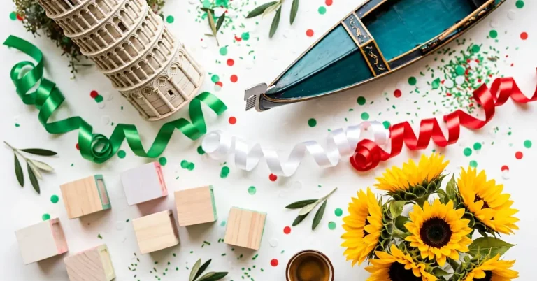 Vibrant Italian-themed flat lay with leaning tower miniature, gondola, green-white-red ribbons and alphabet blocks in bold saturated colors
